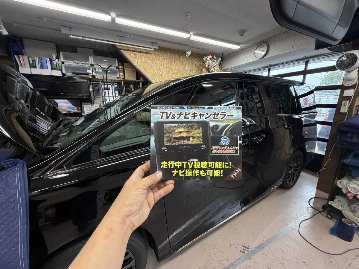 トヨタ ヴェルファイア 6AA-TAHA4#系のHUD搭載車に対応した、エンラージのTV＆ナビキャンセラー Ver.3.0 TV-11です。
走行中でも同乗者の方がTVやDVD、HDMI入力、ミラキャストなどの映像を楽しみやすくなり、ナビ操作にも対応できるので、長距離移動や渋滞中の車内時間がかなり過ごしやすくなります。
この商品の良いところは、単に映像を映せるだけではなく、ステアリングスイッチで機能のON/OFF切り替えができるところです。
後付けスイッチを増やさずに使えるので、見た目もすっきり。ナビ案内や自車位置の動きにも配慮された仕様なので、40系アルファード・ヴェルファイアの純正システムに合わせて使いやすい内容になっています。
取り付けはカプラー接続タイプですが、40系は内装の外し方や復元、配線の通し方で仕上がりのきれいさが変わります。
ログオンでは、見えない部分の配線処理や動作確認まできちんと行い、純正の雰囲気を崩さずに使えるよう施工していきます。こういう便利パーツこそ、付けた後に違和感なく使えることが大事です。
