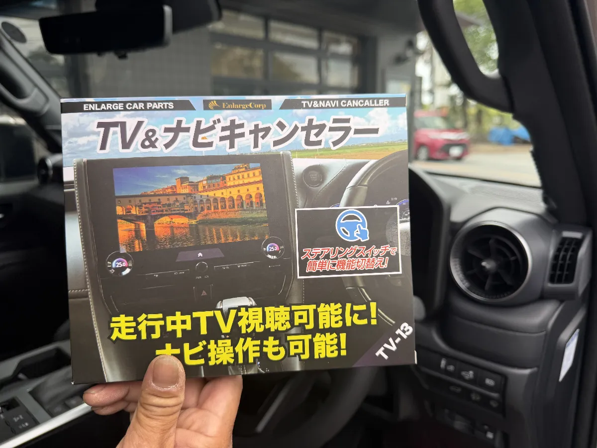 ランドクルーザー250のディスプレイオーディオに対応したエンラージ TV&ナビキャンセラー Ver.3.0 TV-13は、走行中でも同乗者がテレビやHDMI動画を楽しめて、ナビ操作もしやすくなる実用性の高い一台です。長距離移動や渋滞時に「見る人も運転する人も不便」という純正の使いにくさを、自然なかたちで解消してくれます。
このモデルは機能面だけでなく、使い方までよく考えられているのがポイントです。ステアリングスイッチでON/OFFを切り替えられるので、後付けスイッチを増やさず見た目もすっきり。さらに車両配線を傷めにくいカプラーオン設計で、仕上がりのきれいさや今後の安心感にもつながります。
ランドクルーザー250のように移動距離が伸びやすい車だからこそ、走行中の快適性は想像以上に効いてきます。ログオンでは、ただ取付けるだけでなく、車種ごとの配線まわりや使い勝手まで見ながら施工するので、後付け感を抑えつつ気持ちよく使える状態でお渡しできます。付けたあとに「もっと早く入れておけばよかった」と感じやすい、満足度の高い実用パーツです。